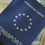 A high-tech airport gate in Europe where a traveler is using a smartphone to scan a QR code from their EU Digital Identity Wallet at a biometric EES kiosk.